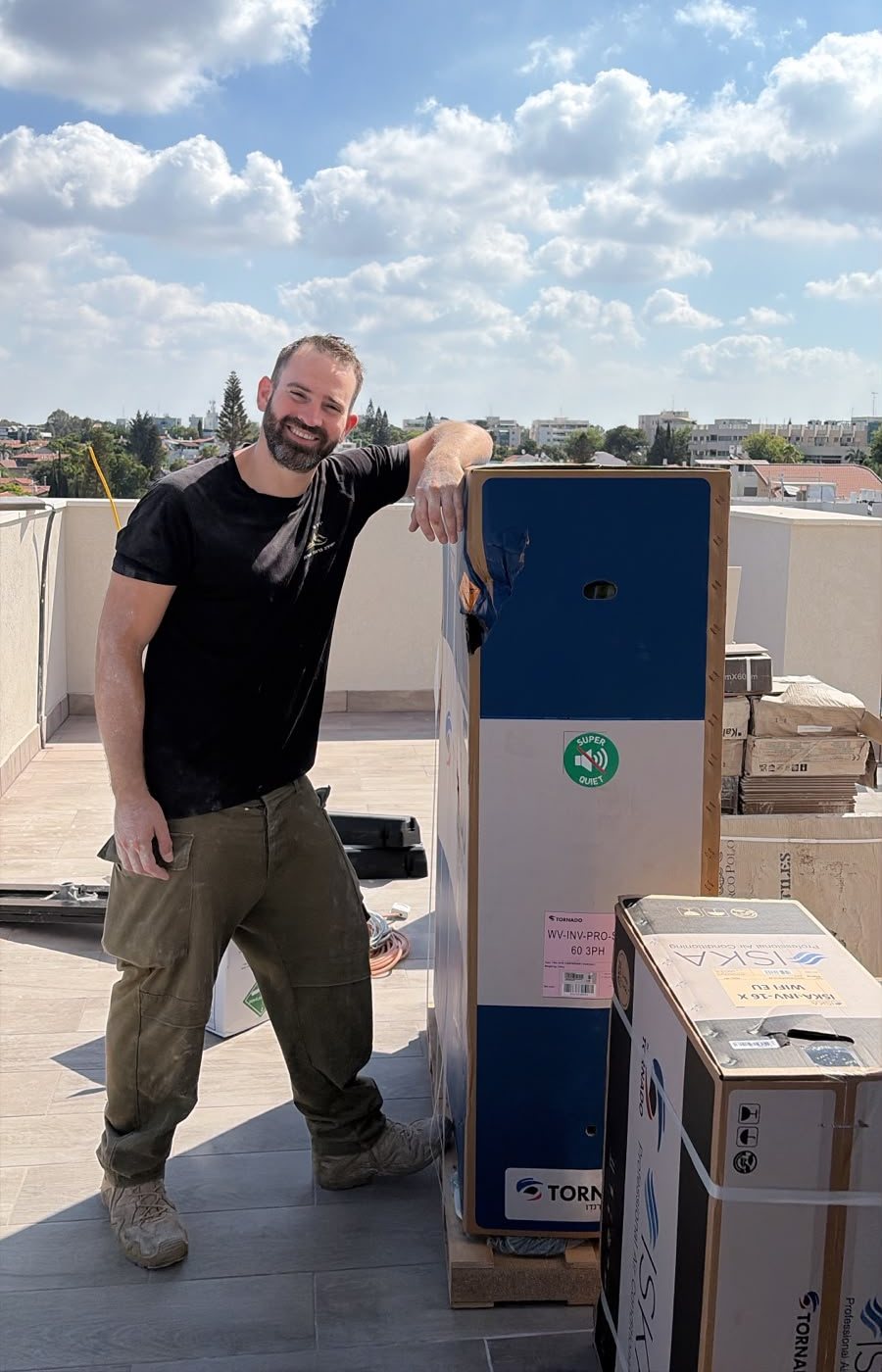 ישראל, בעל המקצוע שמאחורי IsraFix, על גג בניין לצד יחידות מיזוג חדשות לפני התקנה